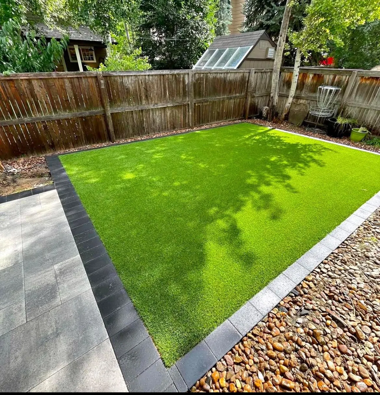 A backyard with artificial turf and a paver border